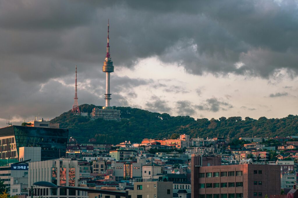 A stunning view of Seoul, South Korea's Namsan Seoul Tower surrounded by city buildings and dramatic clouds.