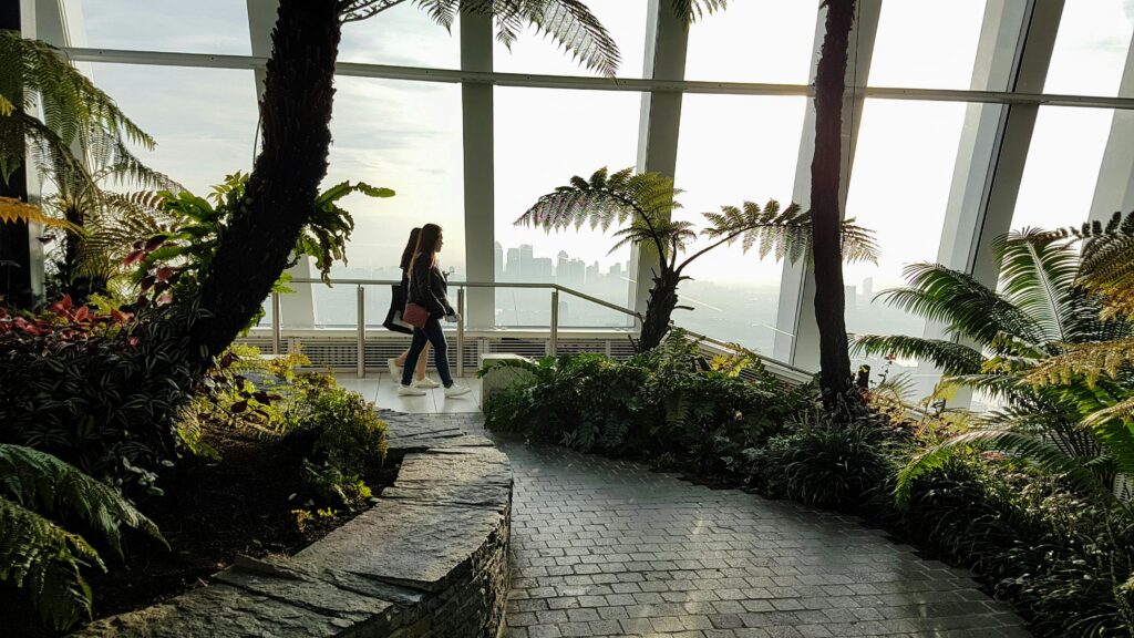 A woman walks through London's Sky Garden, surrounded by lush greenery.