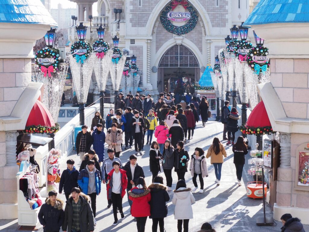 People enjoying a winter day at a decorated theme park entrance with festive Christmas decorations.