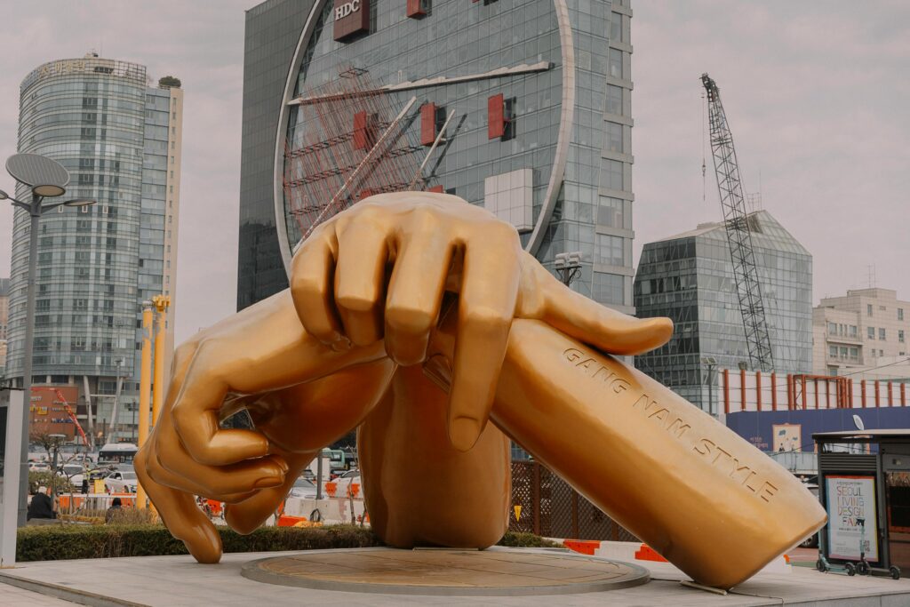 Golden sculpture of hands in Seoul, South Korea, showcasing modern urban architecture.