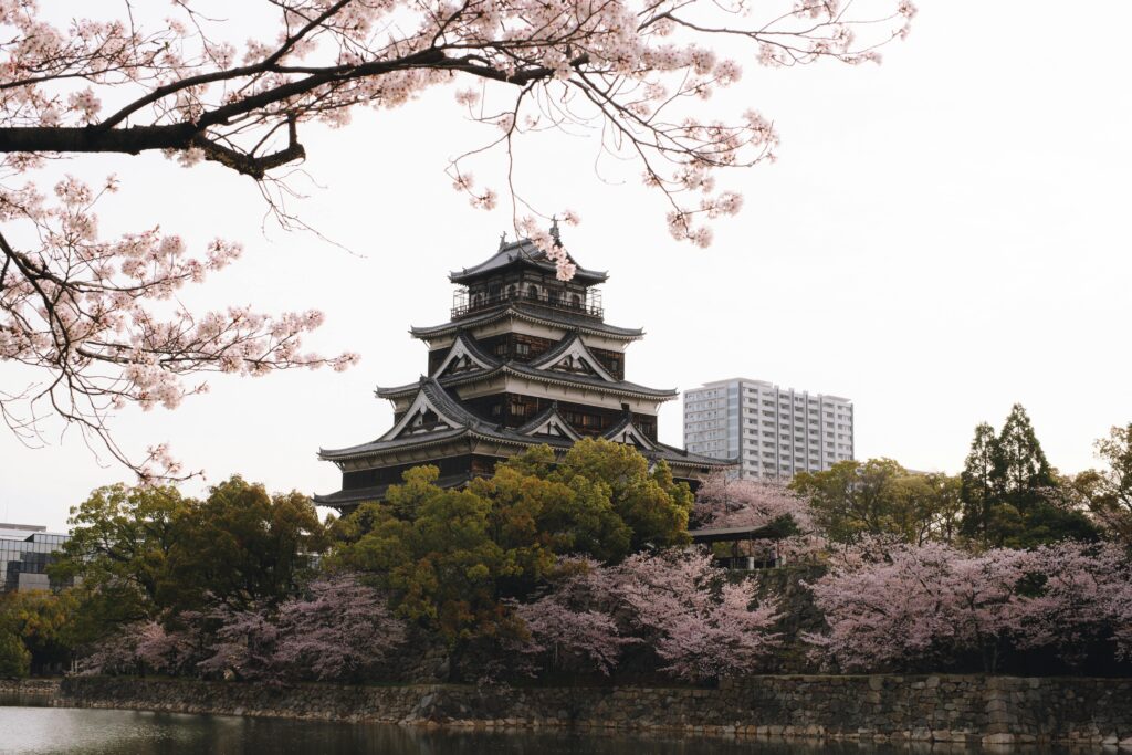 Historic Hiroshima Castle surrounded by blooming cherry blossoms during springtime in Japan.