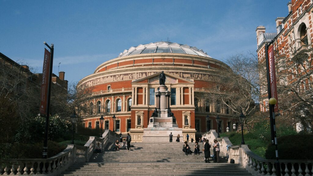 Stunning view of the Royal Albert Hall's exterior with clear blue skies and people enjoying the day.