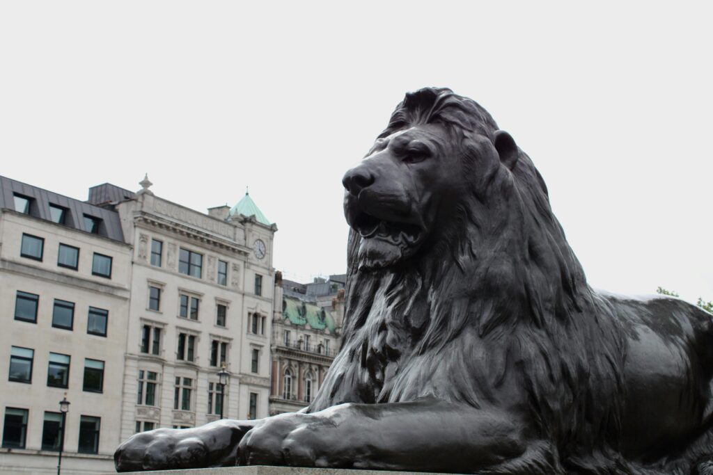 Iconic Trafalgar Square lion statue set against historic London architecture.