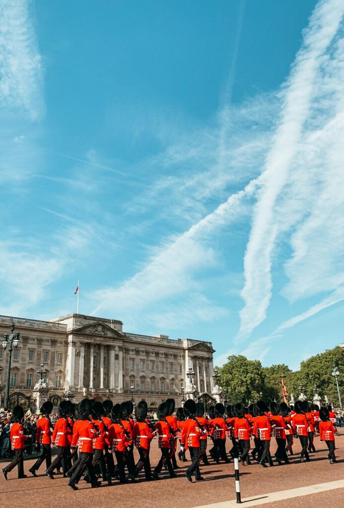 Unrecognizable Queen guards marching on square near palace against cloudy sky on sunny day in UK