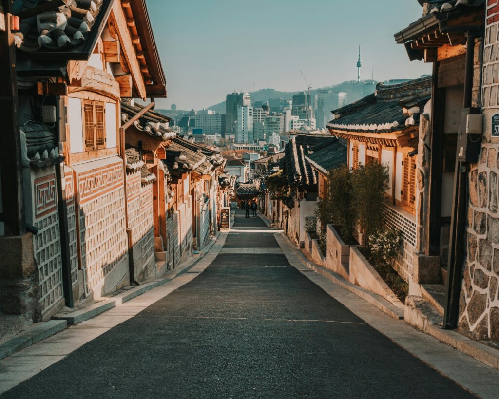 Charming alley in Bukchon Hanok Village showcasing traditional Korean architecture against a modern skyline.
