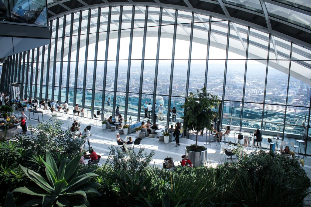 Beautiful indoor garden with panoramic city views, featuring lush plants and seating areas.