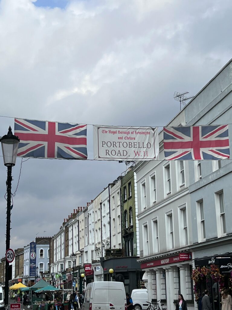 Colorful street scene with Union Jack flags and historic London architecture on Portobello Road.